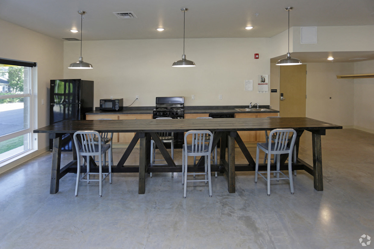 a large communal table with chairs in a room with a kitchen