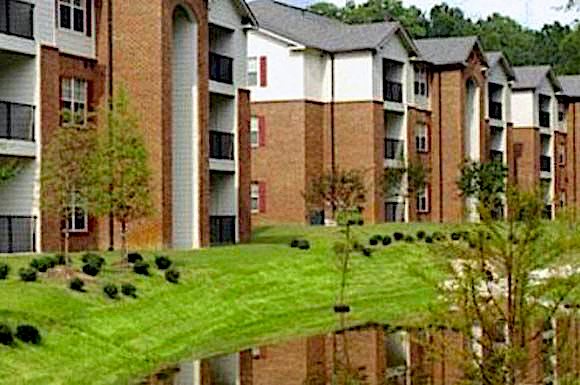 lush landscaping around pond and apartments