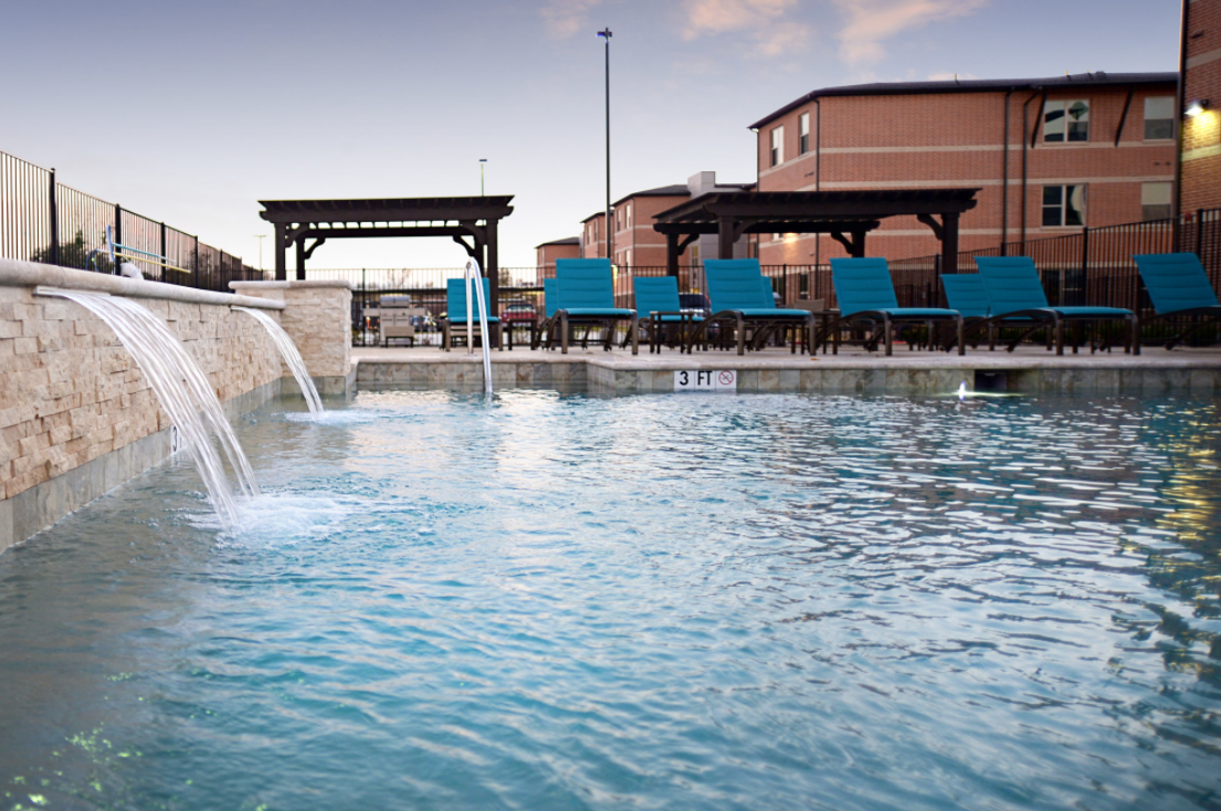 a swimming pool with a water fountain and chairs