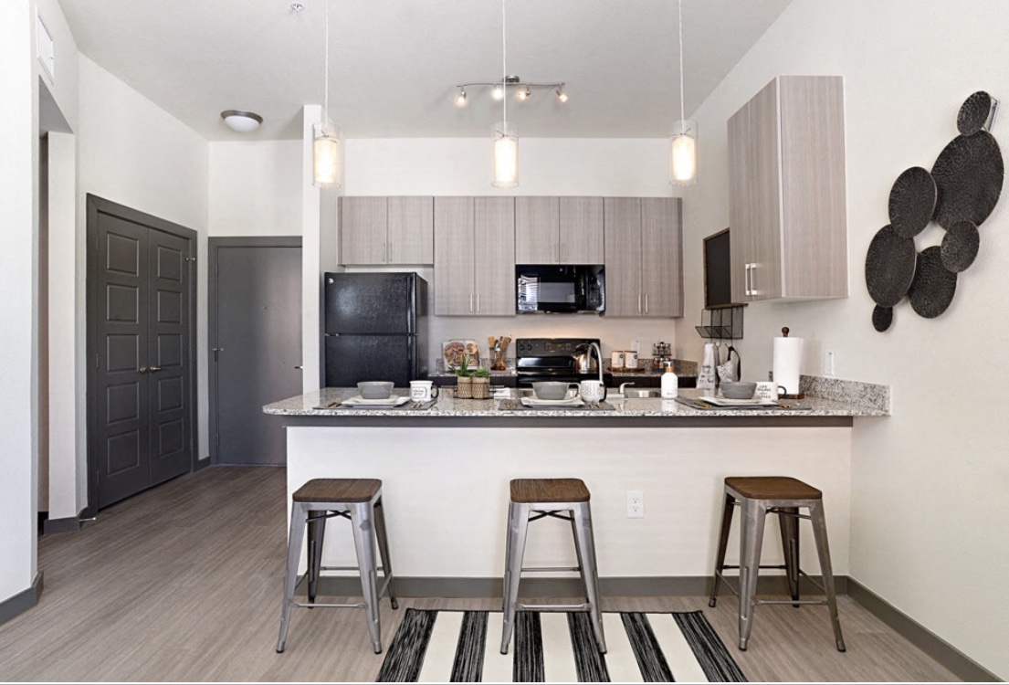 a kitchen with a bar and stools in a modern apartment