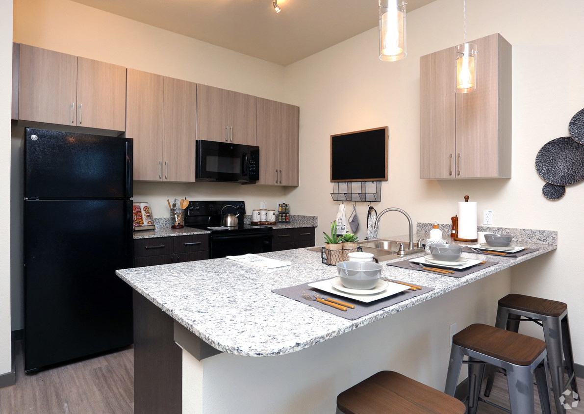 a kitchen with a large island and a black refrigerator