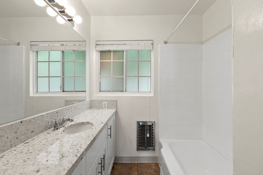 Van Nuys Apartments - Colonial Manor - Grey Countertop, White Bathtub, and Large Mirror