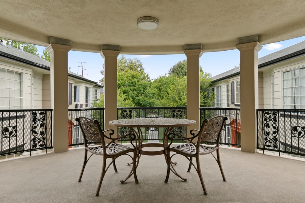 Van Nuys Apartments for Rent - Colonial Manor - Steel Decorative Table and Chairs Set, Black Steel Railing, and Brown Columns