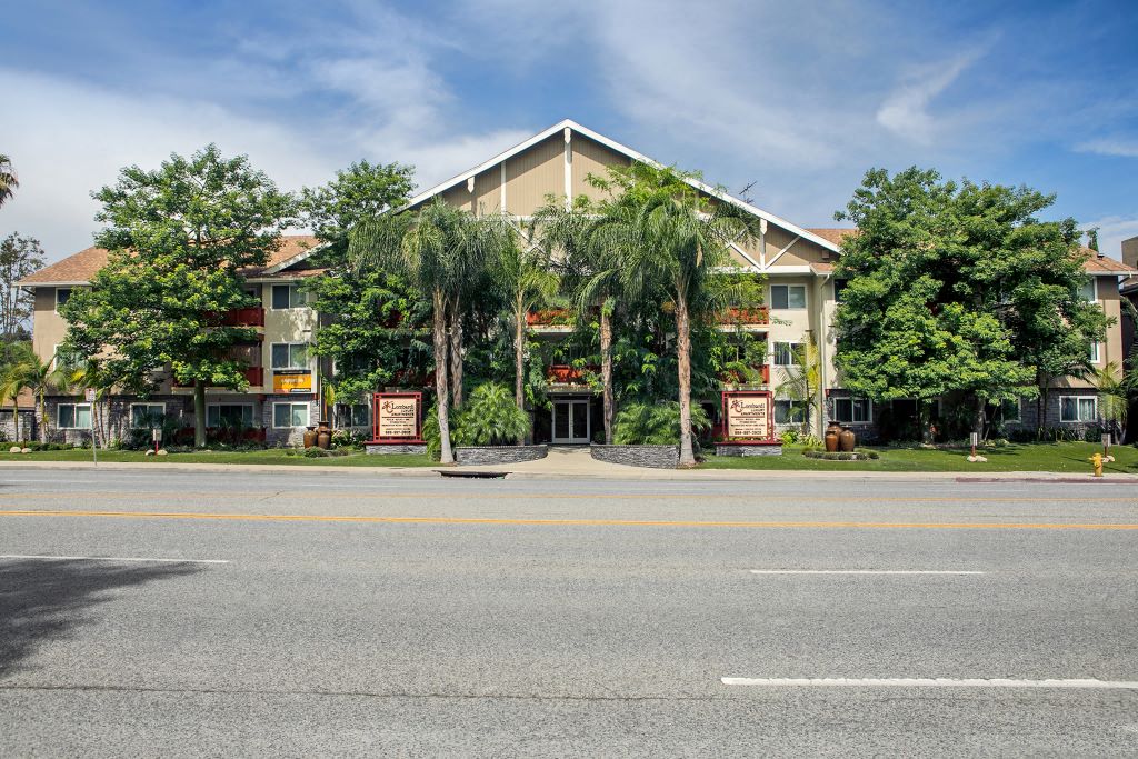 Pet Friendly Apartments in Woodland Hills, CA - Lombardi Apartments Exterior with Lush Greenery and Monument Signs
