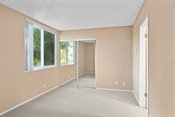 an empty room with a mirrored door and two windows