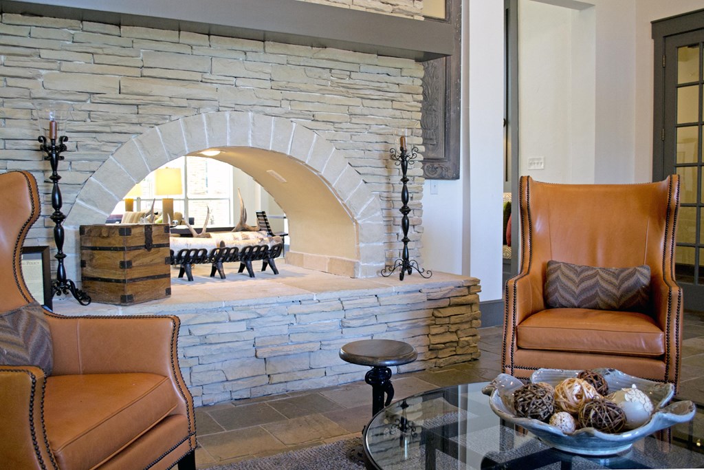 the living room has a stone fireplace and leather chairs