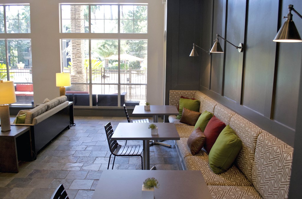 a living room with couches tables and chairs and large windows