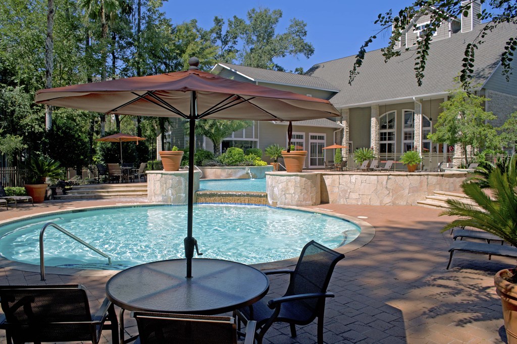 a patio with a pool and table with umbrellas