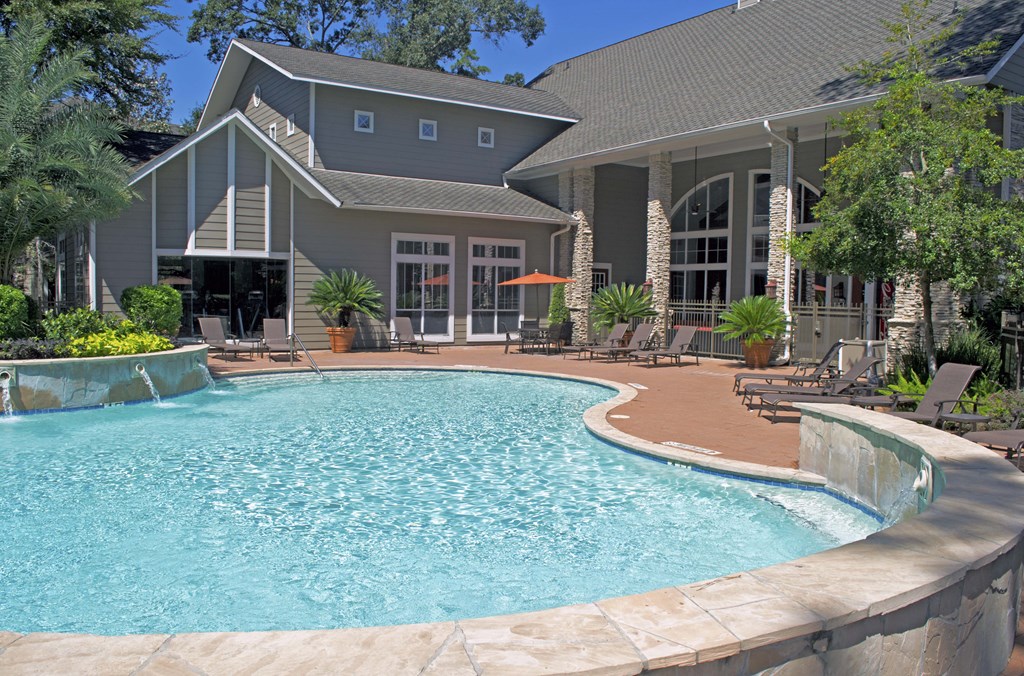The Woodlands TX Apartments for Rent - Whispering Pines Ranch - Resident Swimming Pool With Crystal Clear Water, Lounge Chairs, and Decorative Trees