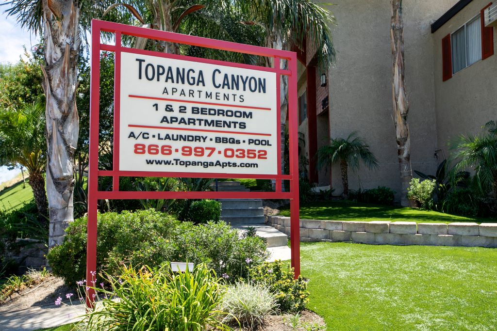 Apartments for Rent in West Hills - Topanga Canyon - Exterior View of Monument Sign with Lush Landscaping and View of Apartment Building
