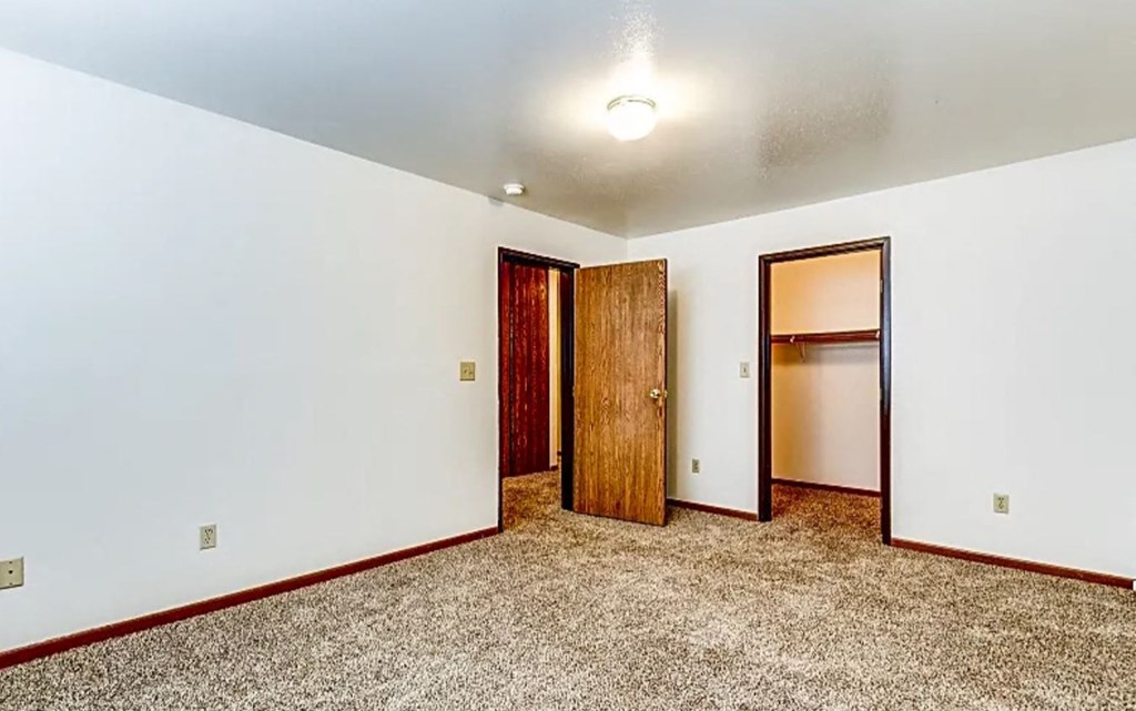 an empty room with a door to a closet and a mirror
