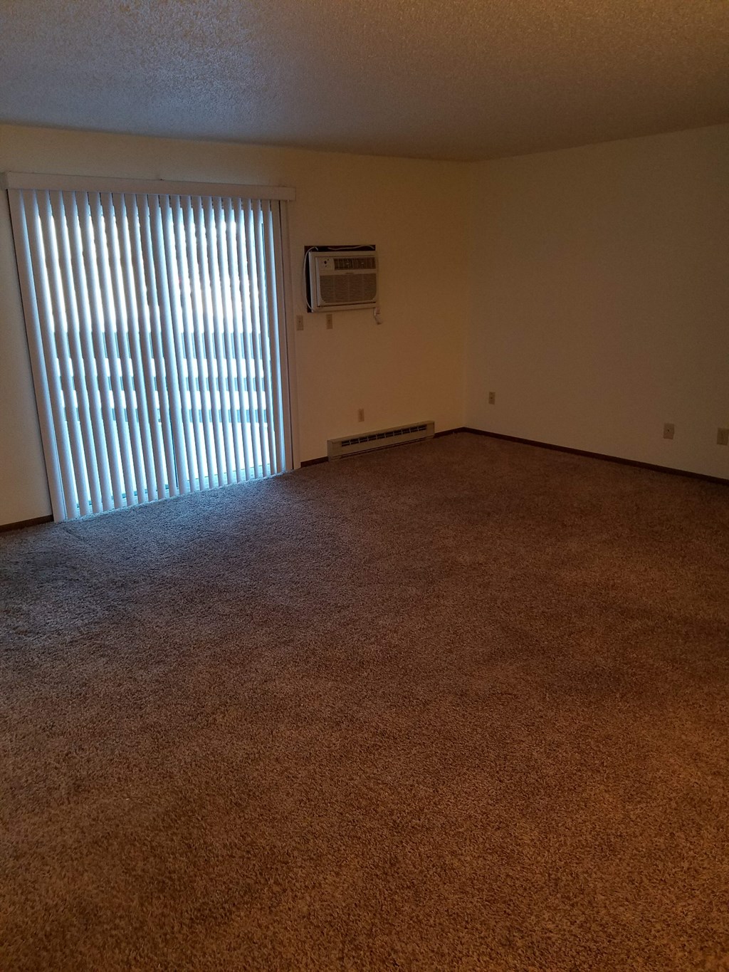 an empty living room with a large window and blinds