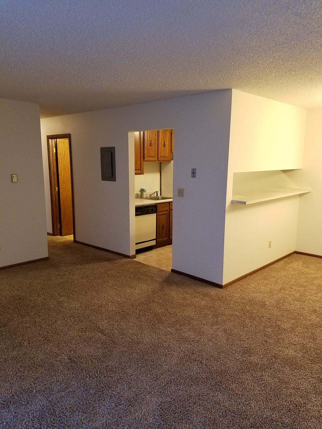 an empty living room with a kitchen in the background