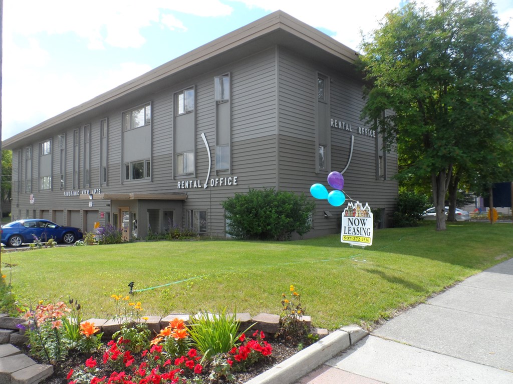 the front of a building with a lawn and flowers