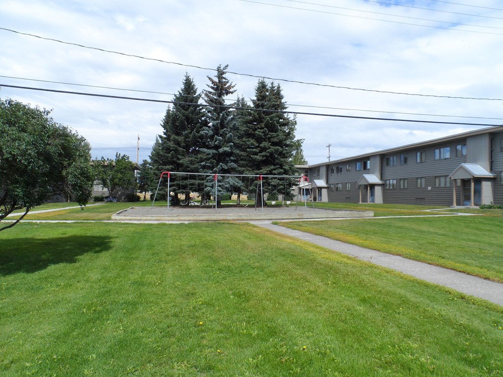 a yard with a swing set in front of a building