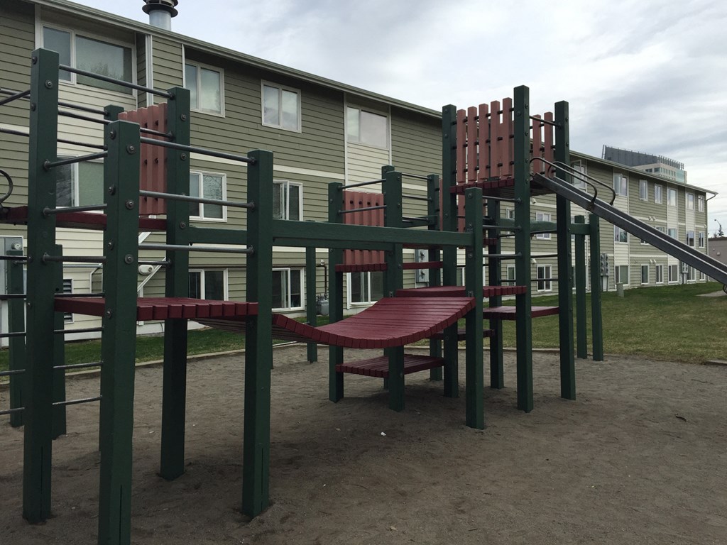 a playground with benches and a slide in front of a building