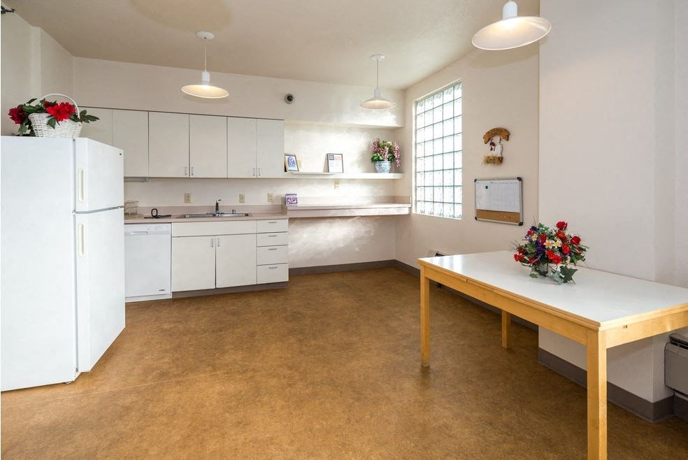 a white kitchen with a table and a refrigerator
