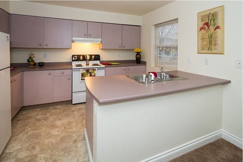 A kitchen with pink cabinets and a white refrigerator.