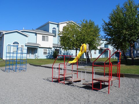 A playground with a red slide and a blue climbing frame.