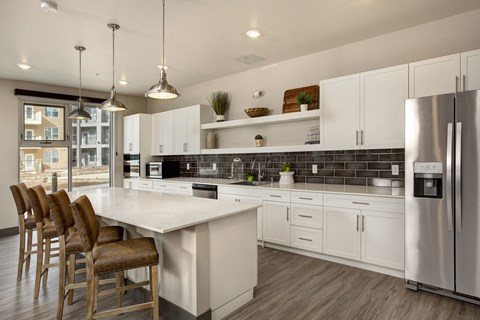 a kitchen with white cabinets and a large island with chairs