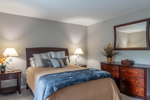 A bedroom with a bed, nightstand, and dresser.