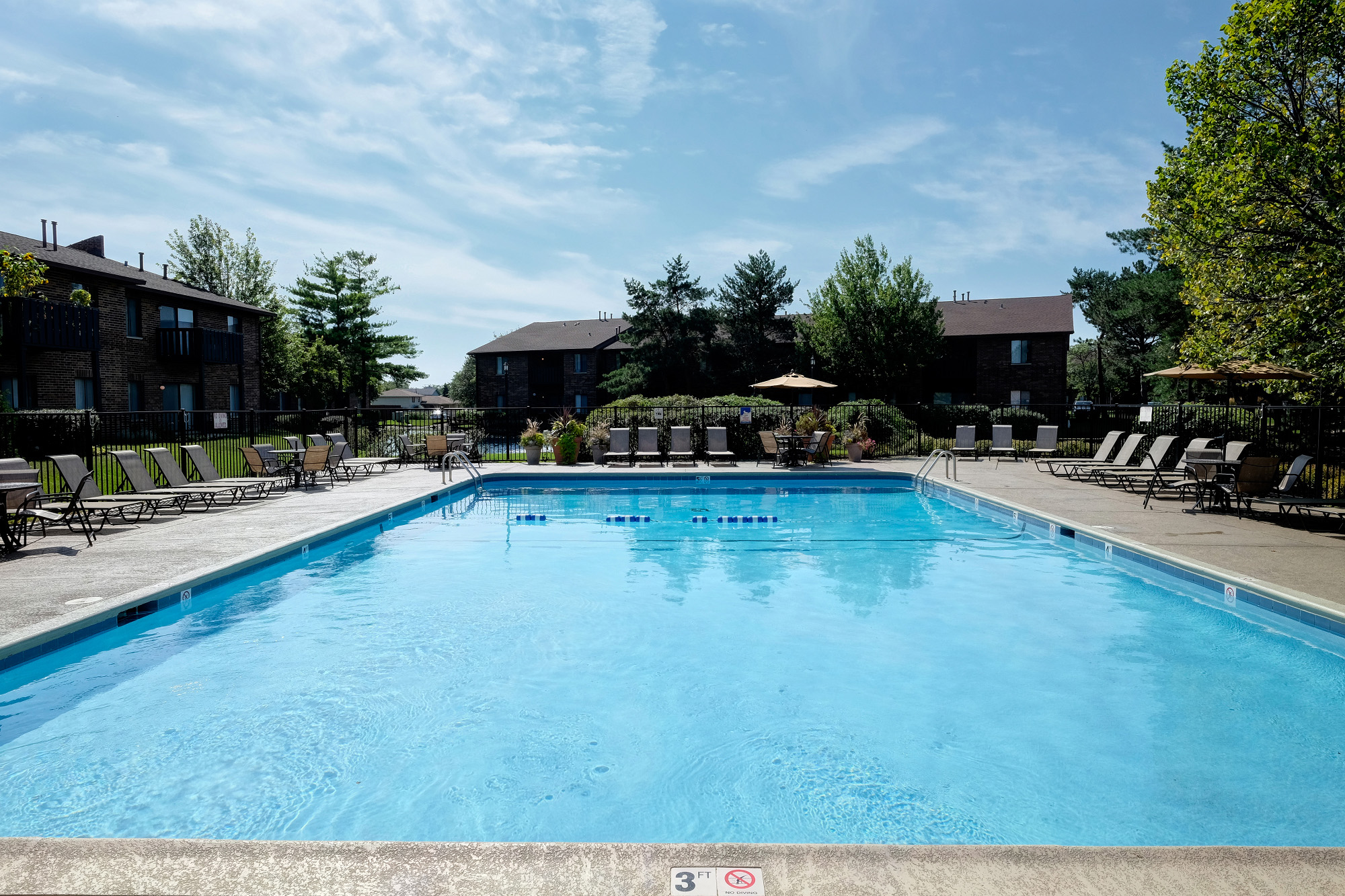 A large swimming pool with a blue water surface and a white fence around it.