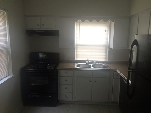 A kitchen with a black oven and white cabinets.