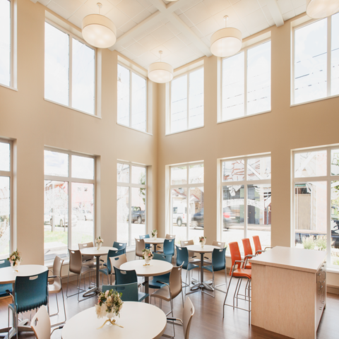 a dining room with tables and chairs and large windows