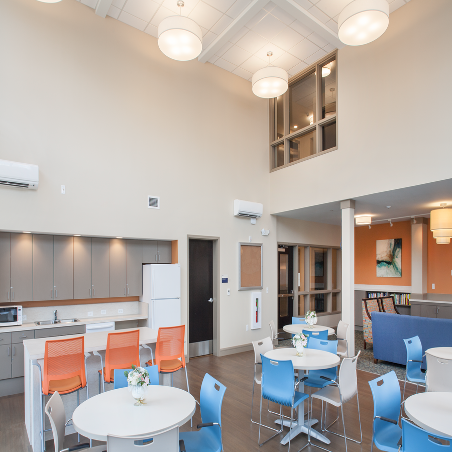 a communal area with tables and chairs and a kitchen