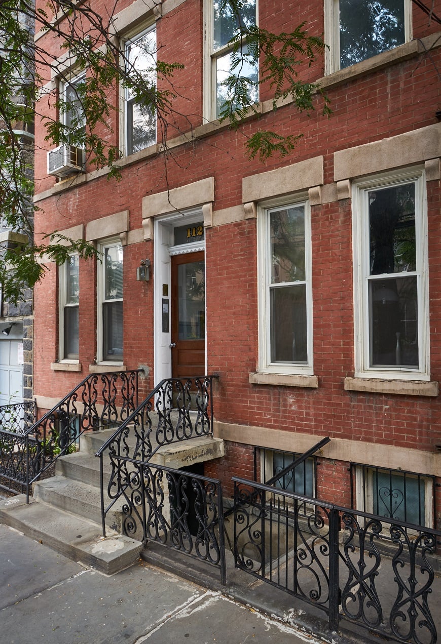A red brick building with a black iron fence.