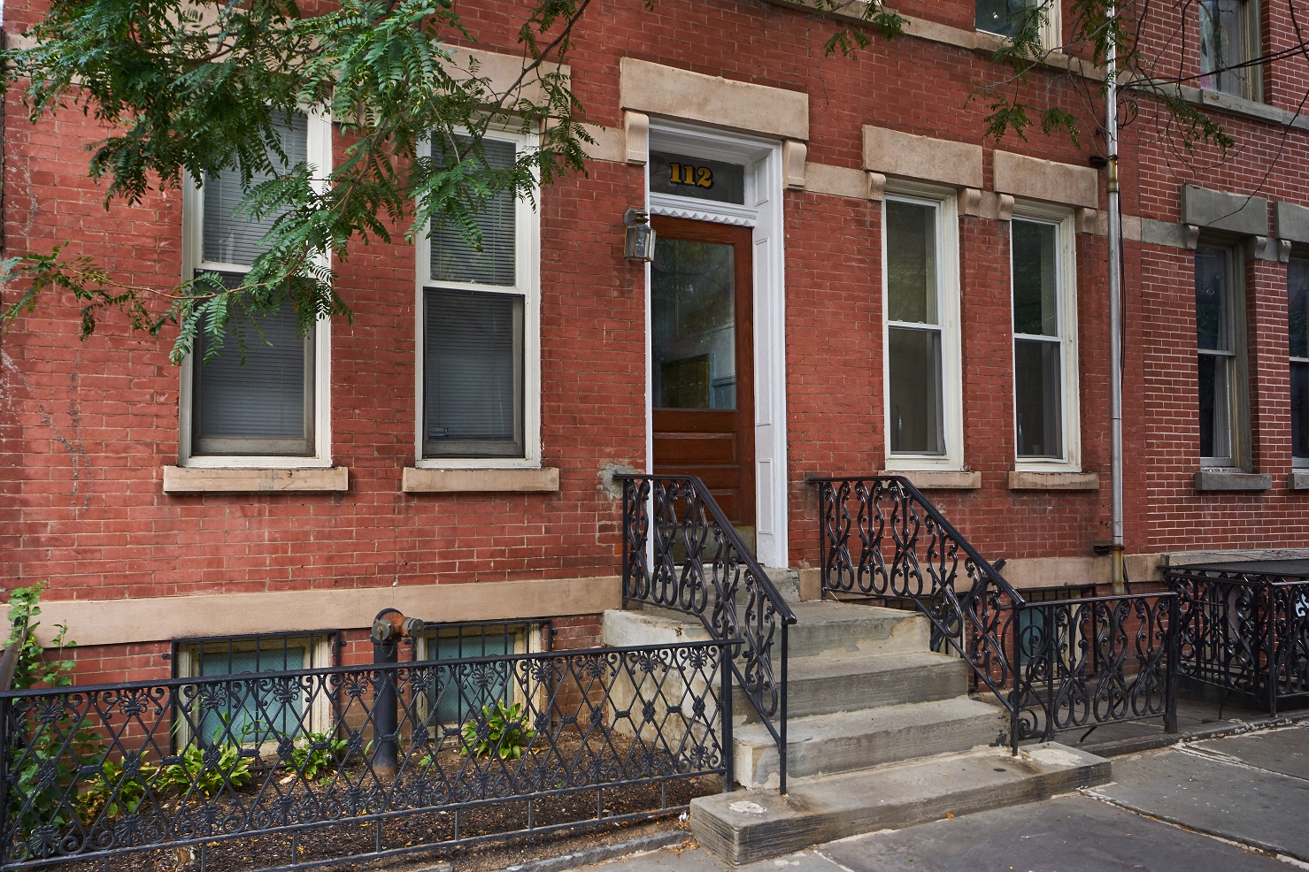 A red brick building with a black iron fence in front.