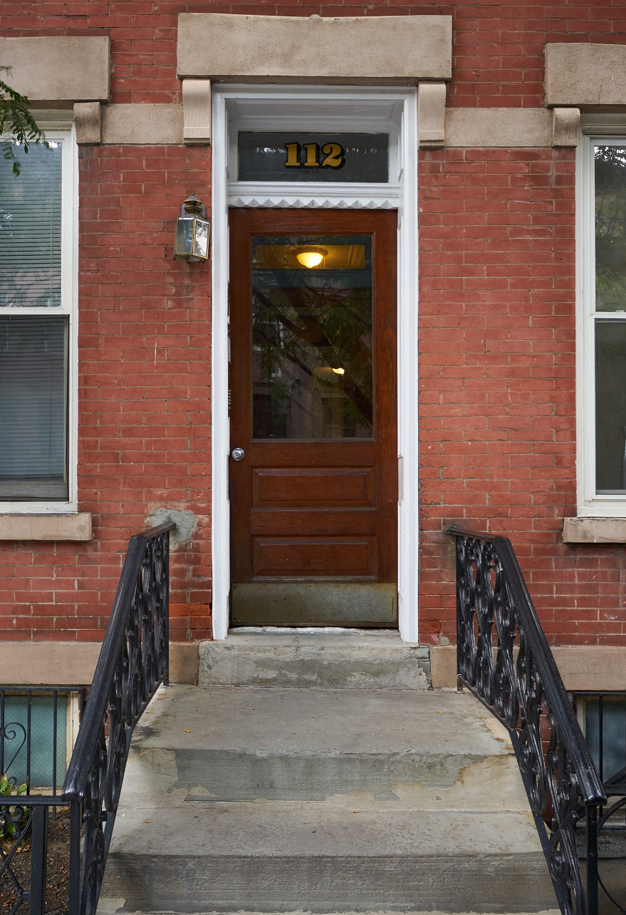 A red brick building with a black iron railing and a black door.
