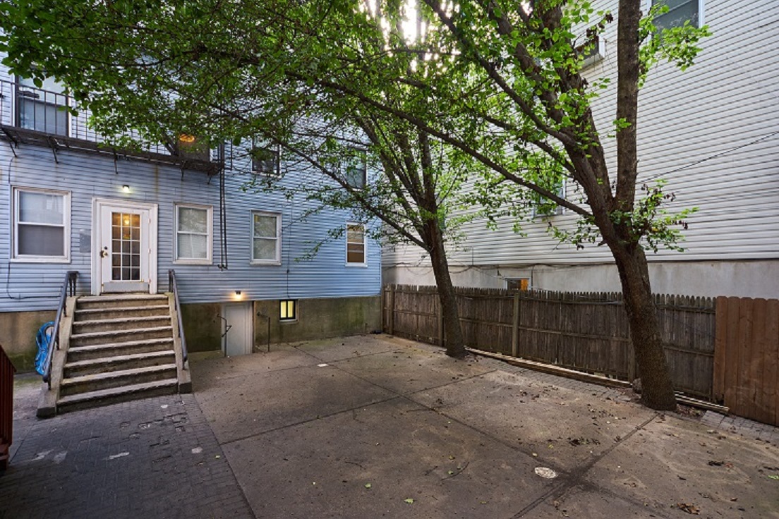 A tree in front of a blue house with a white door.