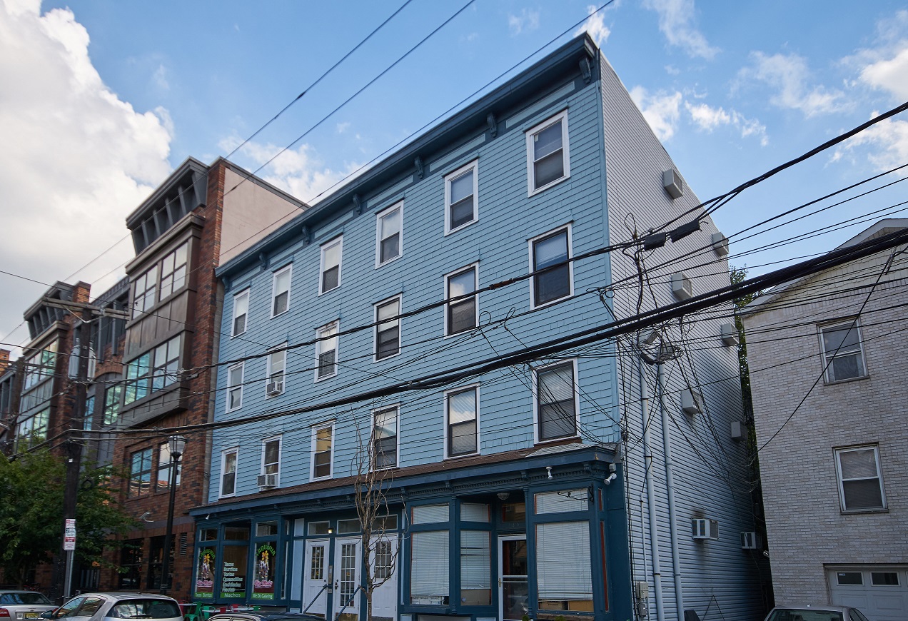 A blue building with a white roof is in the foreground with a clear blue sky above.
