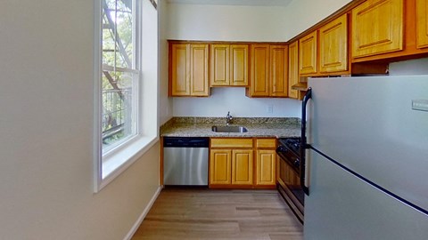 A kitchen with wooden cabinets and a stainless steel refrigerator.