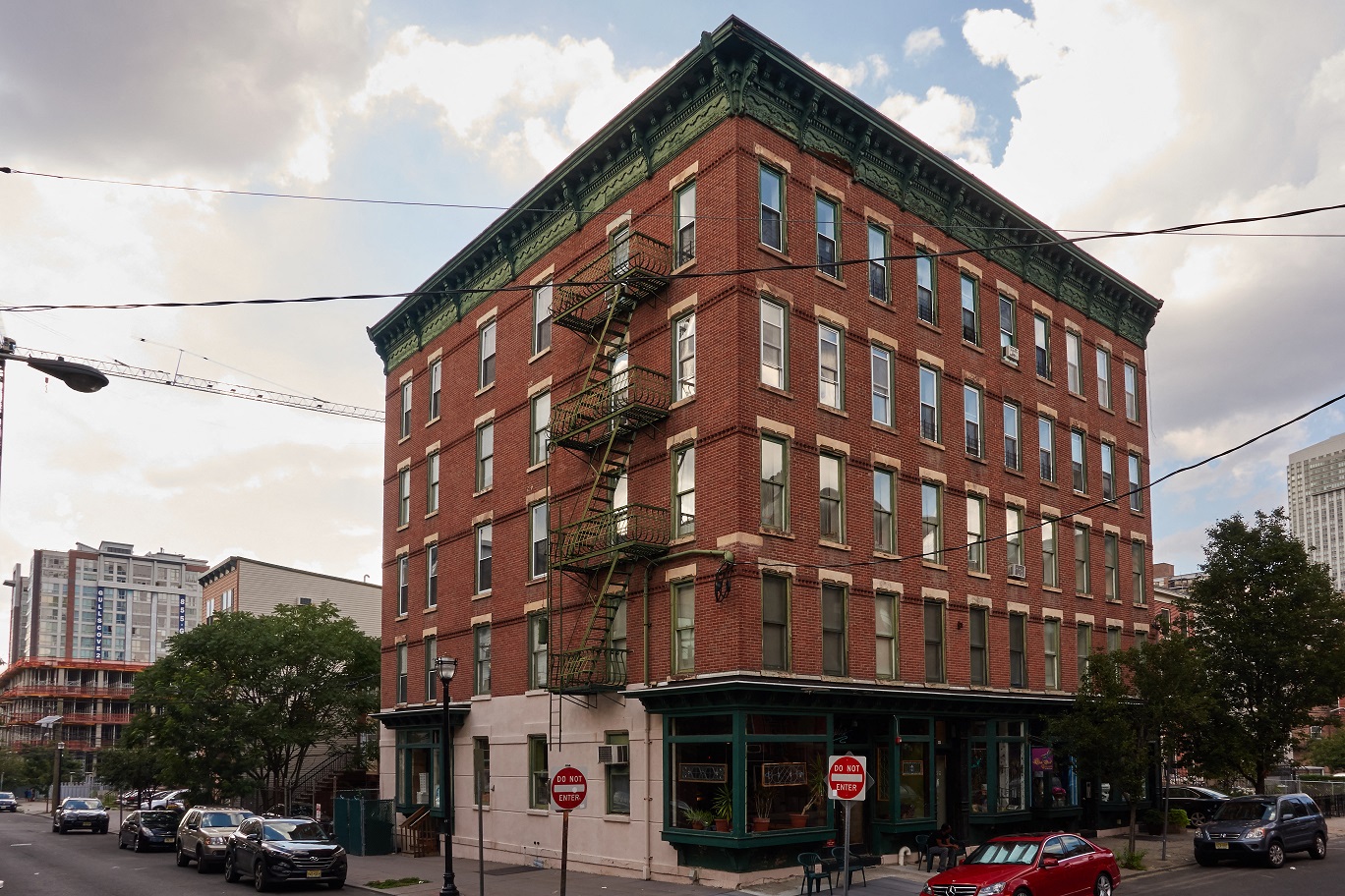 A red brick building with a green roof and a fire escape on the side.