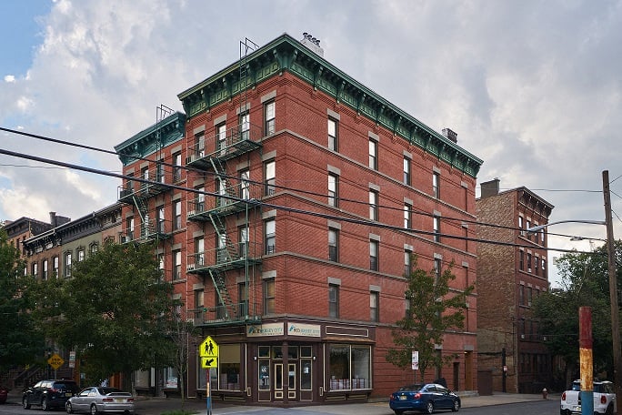 A red brick building with a green roof and a sign that says "Hotel".