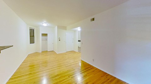 A long hallway with wood floors and white walls.