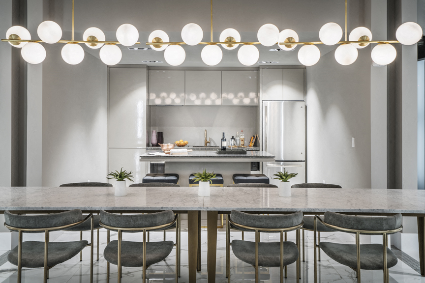 A modern kitchen with a marble countertop and gold chairs.
