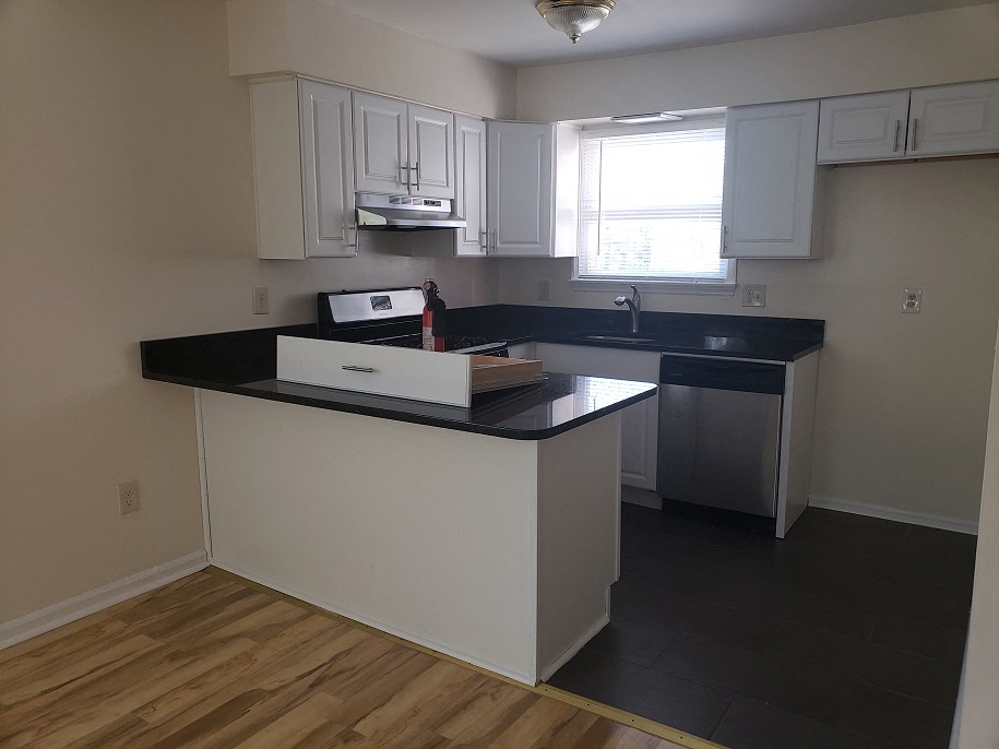 A kitchen with white cabinets and a black countertop.