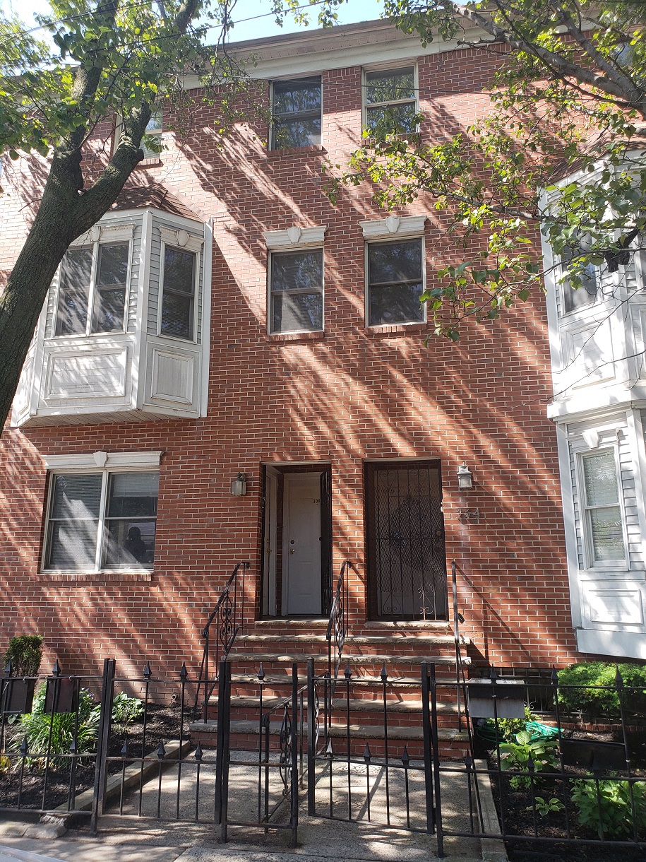 A red brick house with a white window and a brown door.