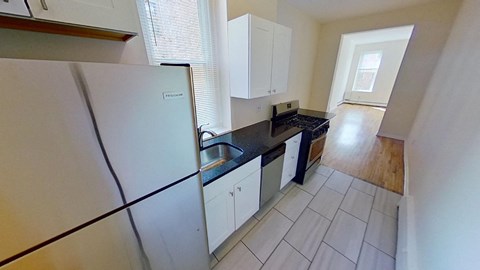 A kitchen with white cabinets and a black countertop.