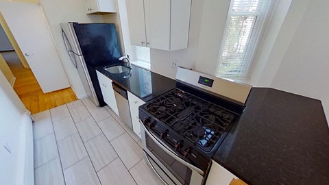 A kitchen with a black stove top oven and white cabinets.