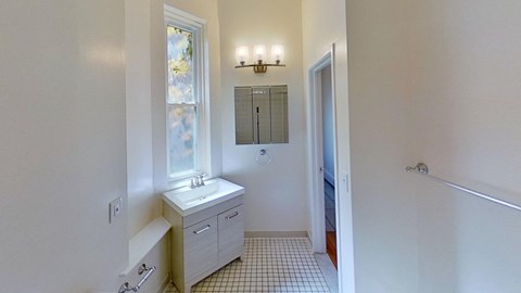 A bathroom with a white sink and a window.