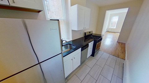 A kitchen with white cabinets and a black countertop.