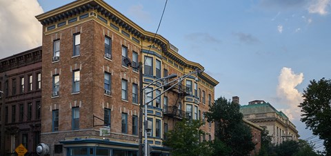 A tall brick building with a yellow trim and a green roof.