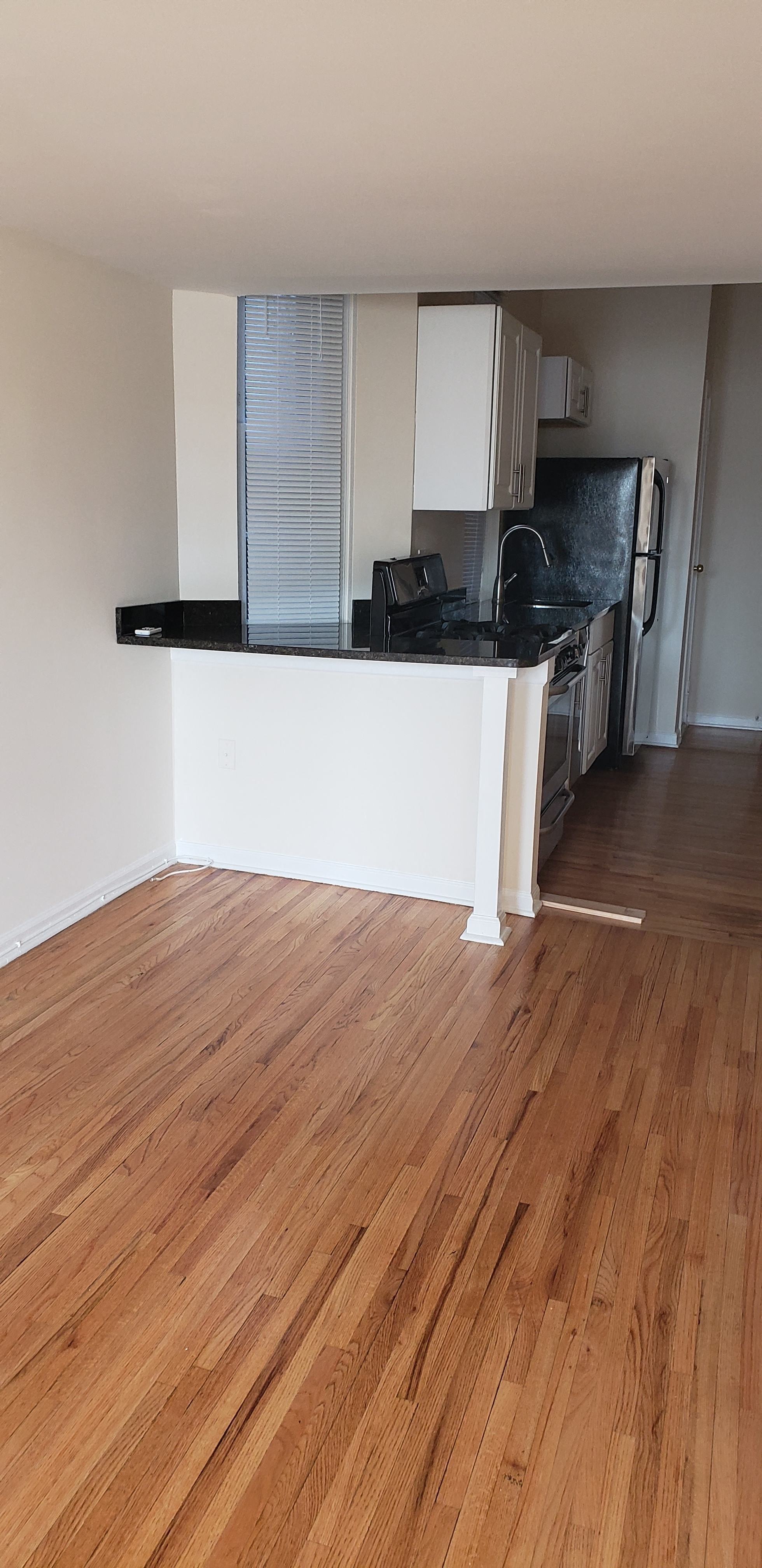 A kitchen with a black counter top and wooden floors.