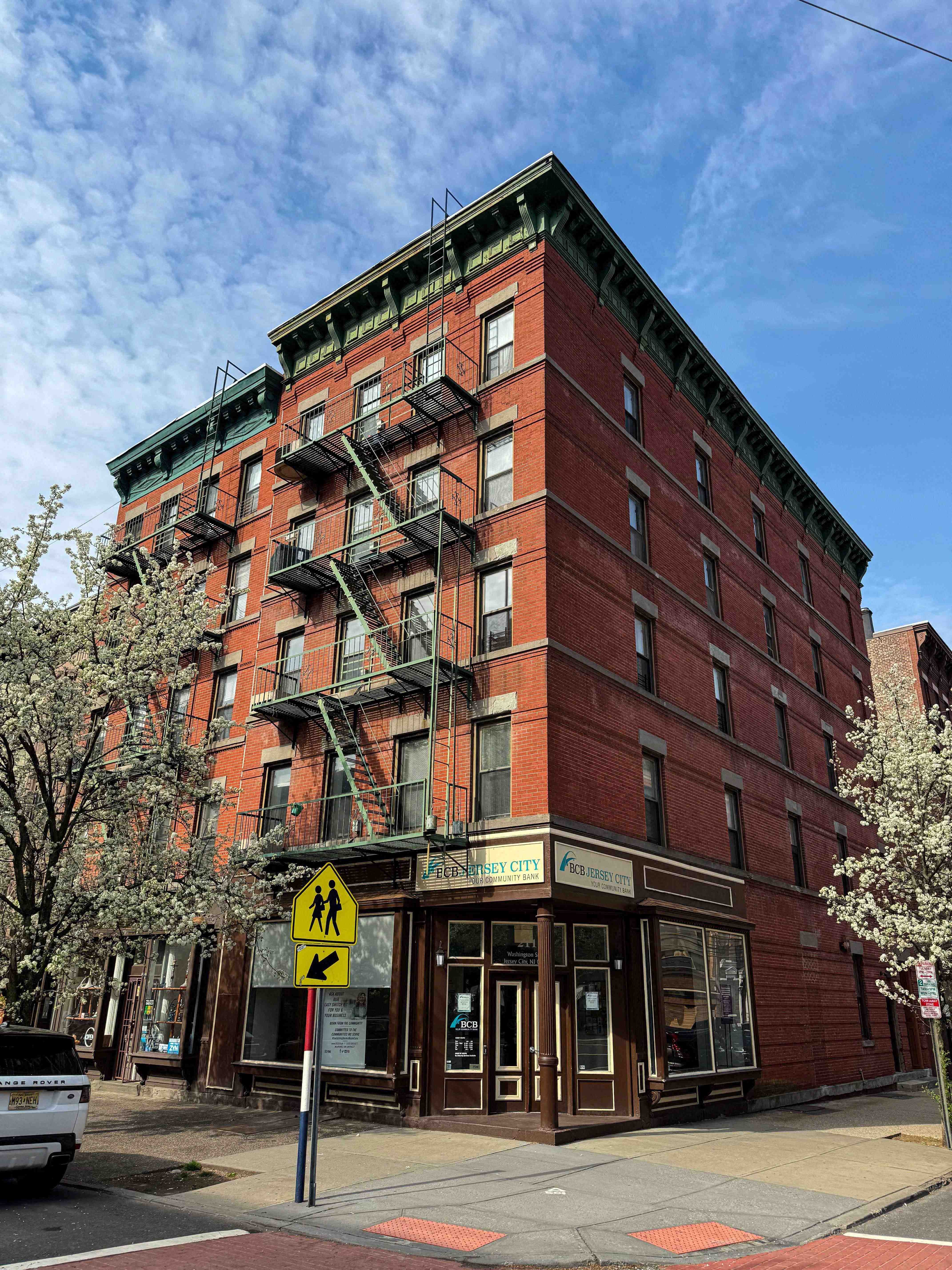 A red brick building with a yellow pedestrian crossing sign in front of it.