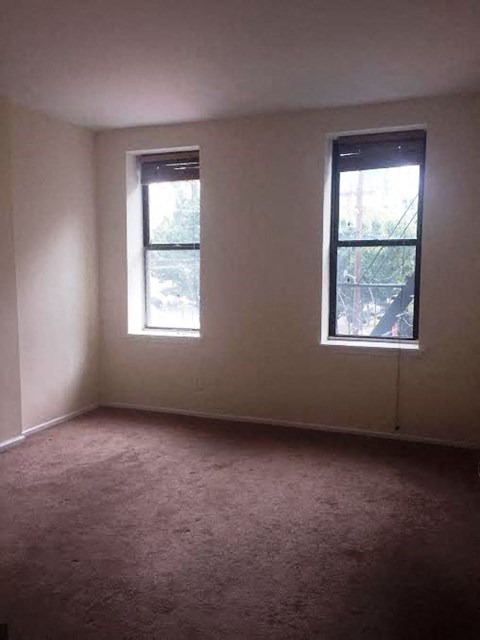 A room with two windows and carpeted floor.