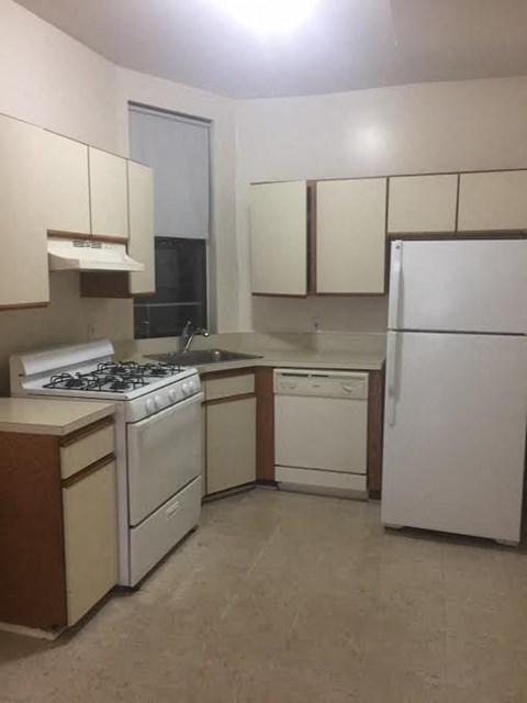 A kitchen with white appliances and wooden cabinets.